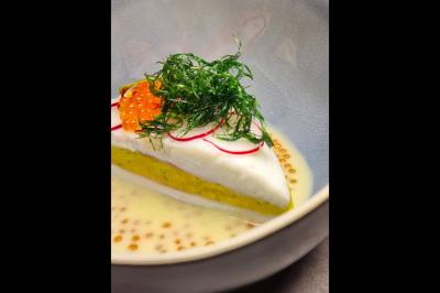 Assiette gastronomique avec saumon, mousse blanche, herbes fraîches et sauce jaune décorée de points verts.