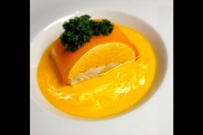 Assiette gastronomique avec saumon, mousse blanche, herbes fraîches et sauce jaune décorée de points verts.