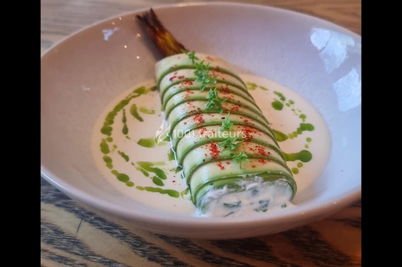 Rouleau de courgette garni, présenté sur une sauce blanche avec des gouttes d'huile verte et une touche de paprika.