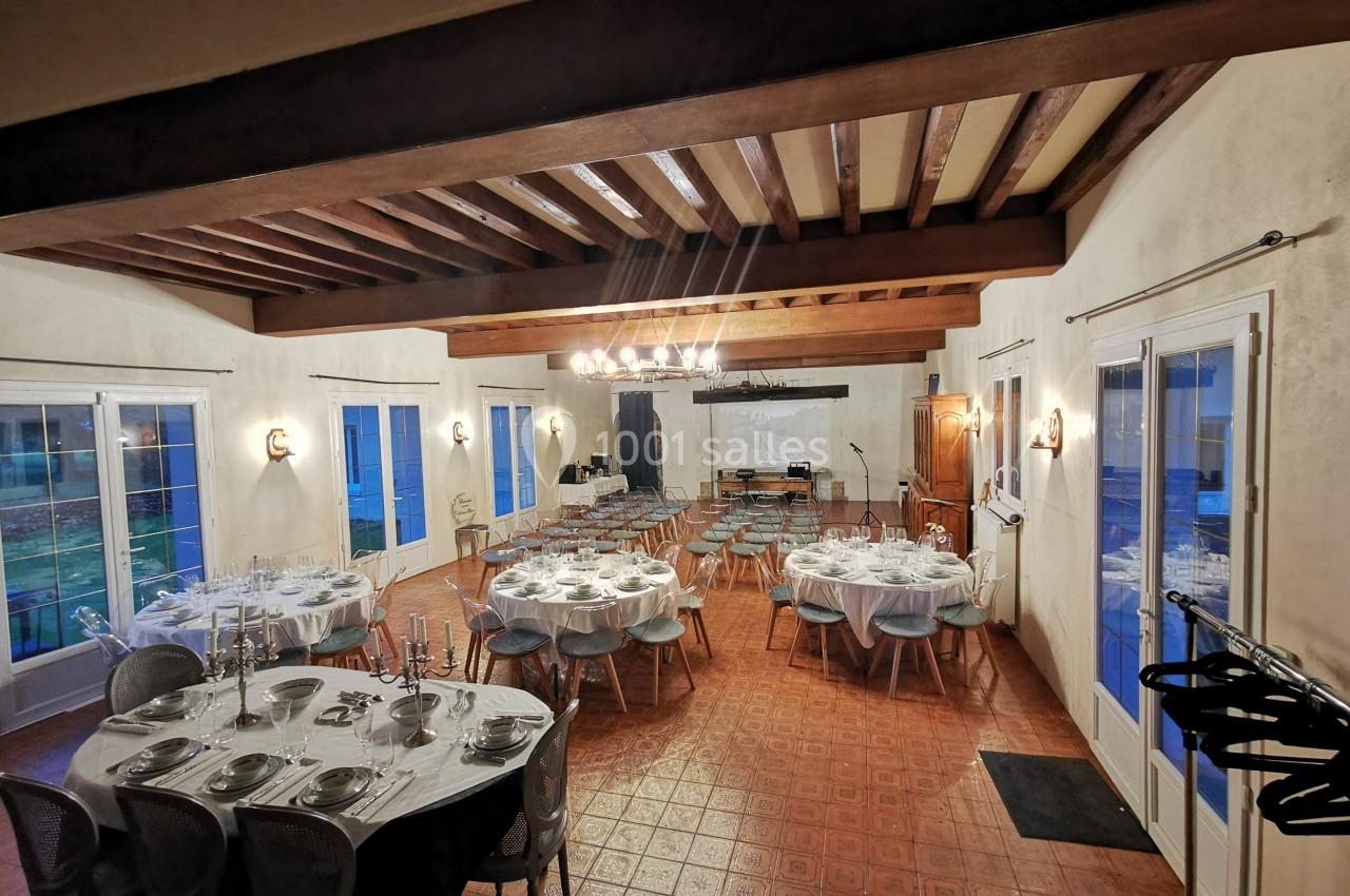 Salle de réception aménagée avec des tables dressées et des chaises disposées pour un événement.