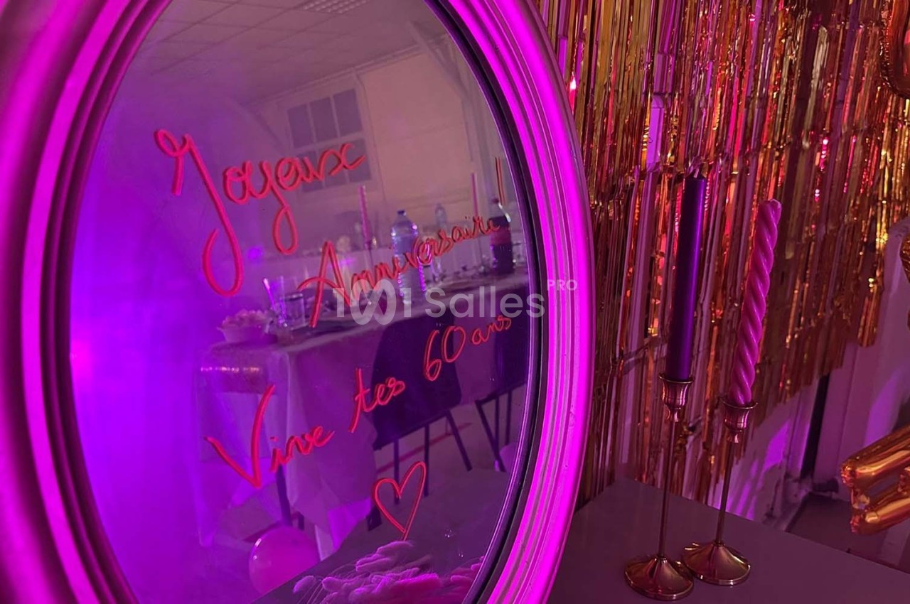 Texte alt : Miroir décoré avec l'inscription ’Joyeux Anniversaire, Vive tes 60 ans’ reflétant une table de fête et des…