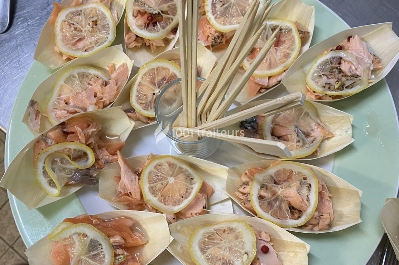 Assortiment de bouchées au saumon et citron présentées dans des coupelles en bois avec des piques en centre.