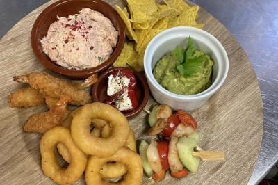 Plateau de fruits variés avec pastèque, ananas, raisins et fraises, disposés sur une table décorée.