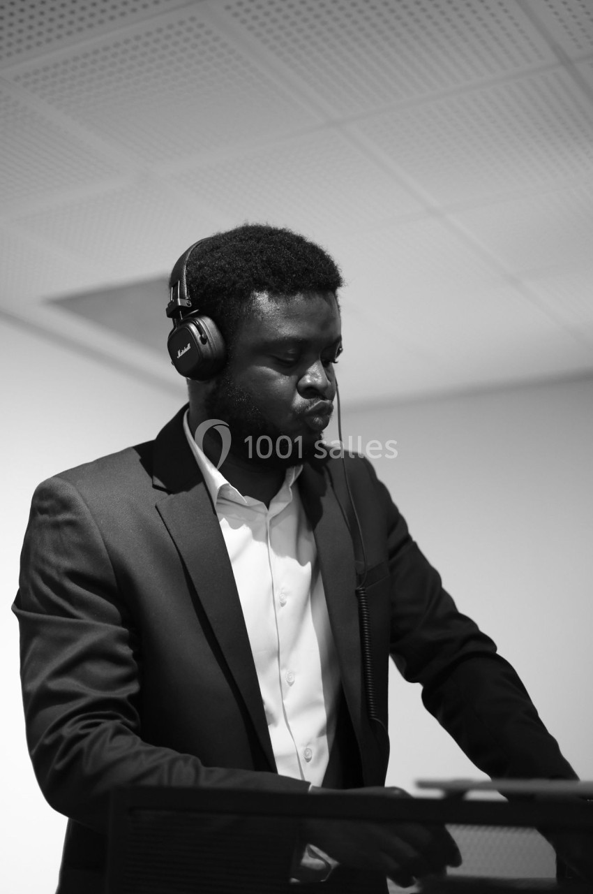Un homme en costume écoute avec concentration au casque tout en manipulant un équipement devant lui.