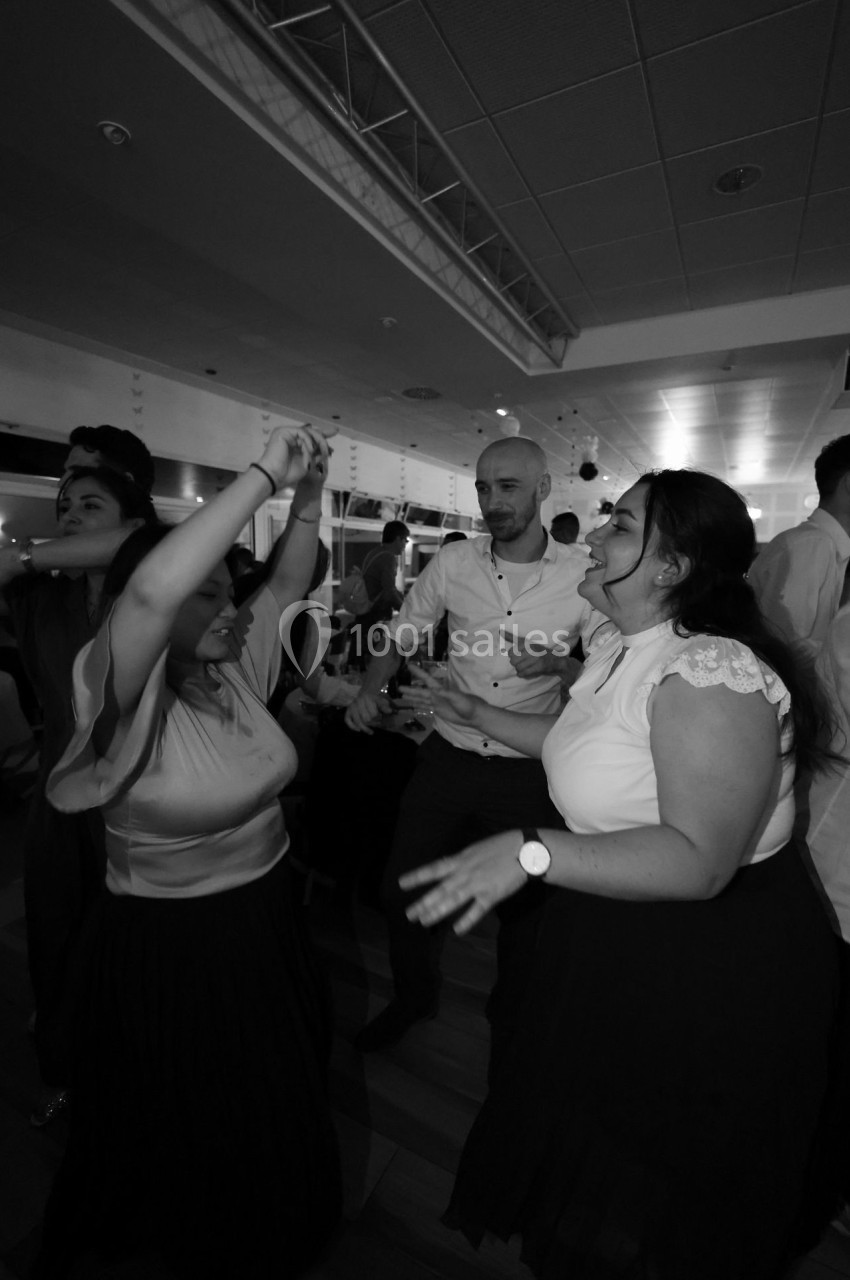 Des personnes dansent ensemble dans une salle éclairée, créant une ambiance festive et conviviale.