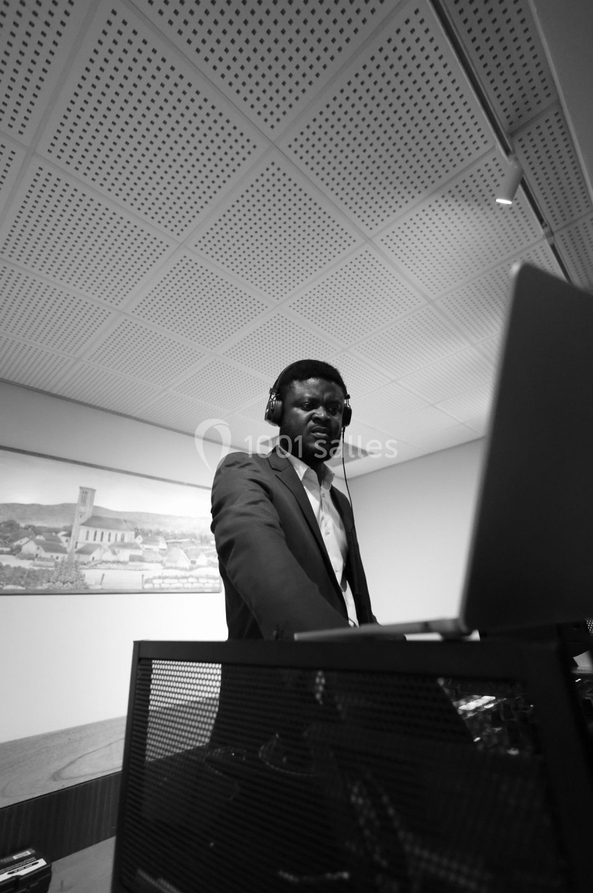 Un homme en costume utilise un ordinateur portable, portant un casque audio, dans une pièce moderne.