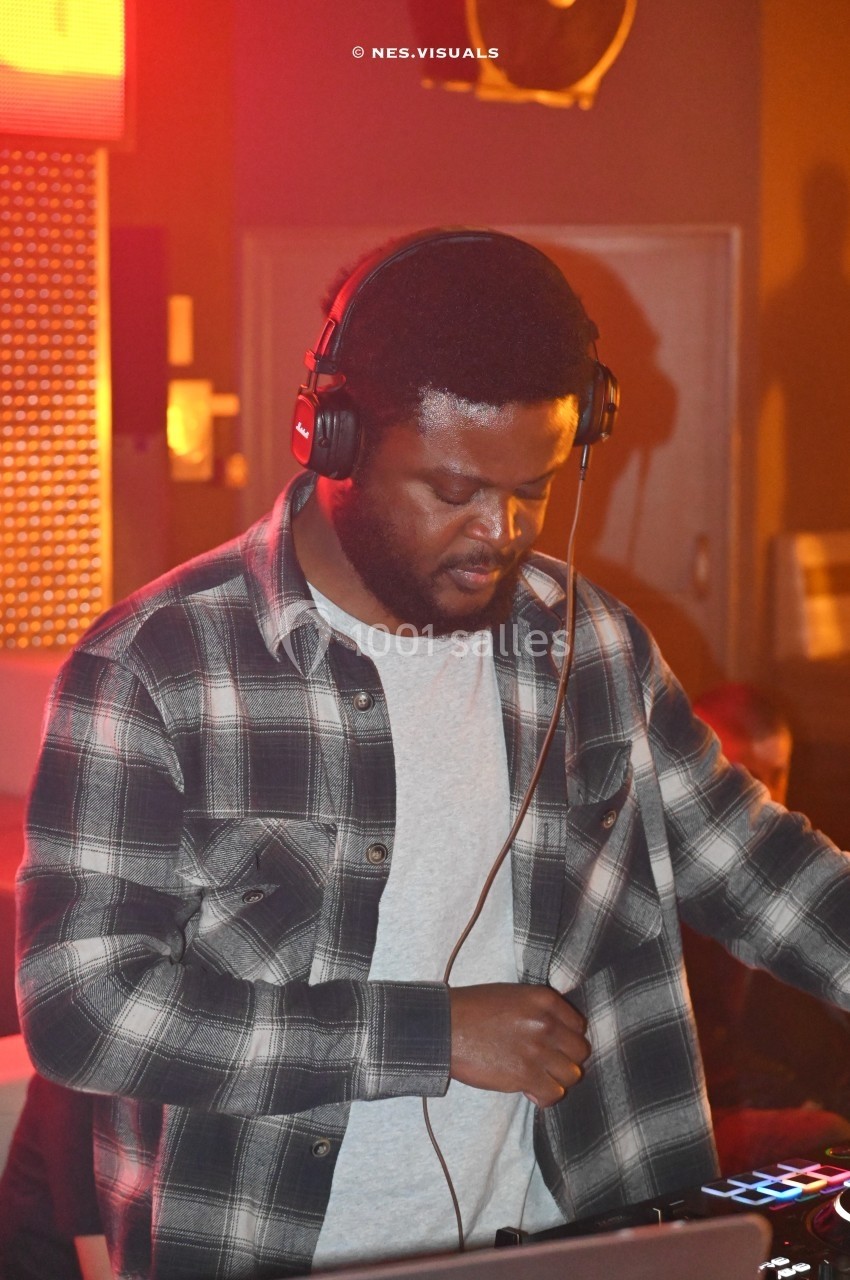 Un homme portant un casque audio mixe de la musique sur une table de mixage dans un environnement lumineux.