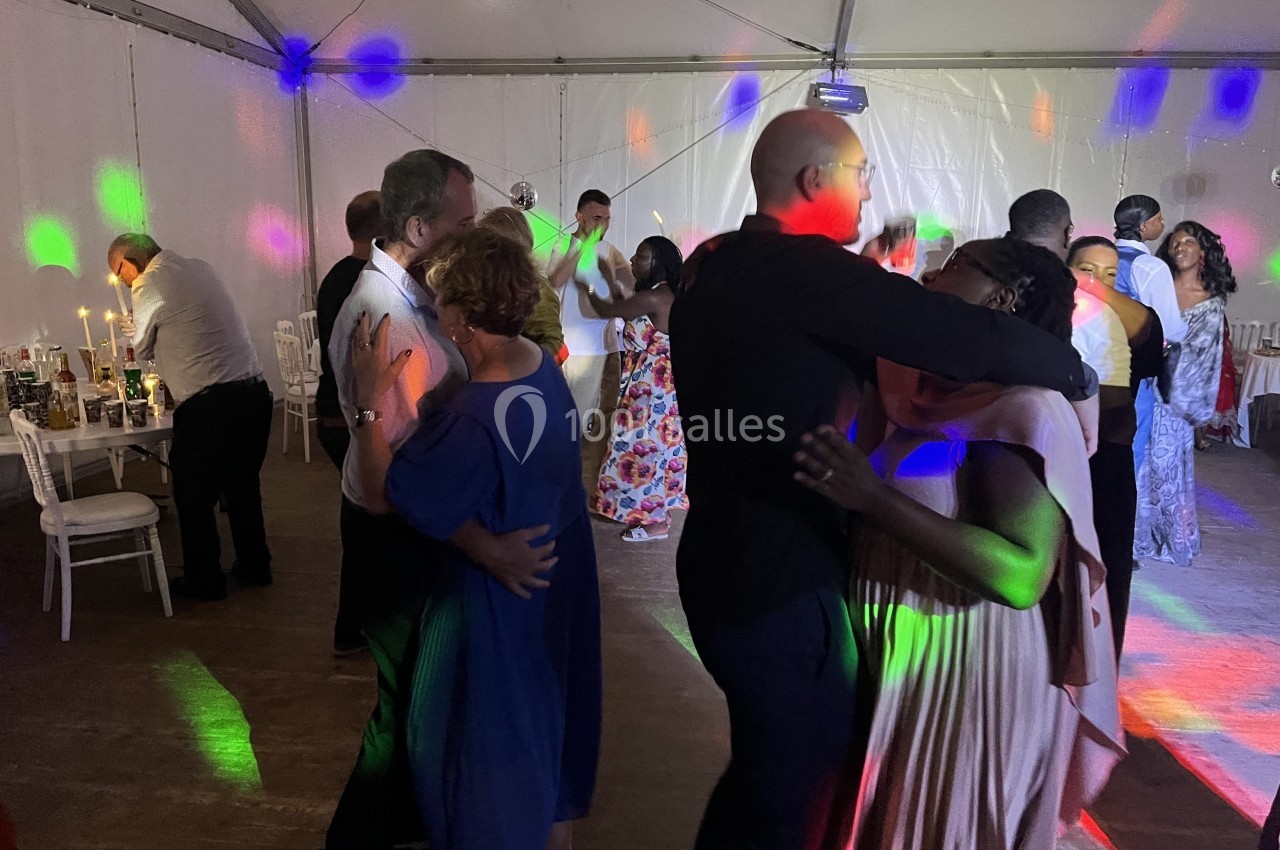 Personnes dansant sous des lumières colorées dans une salle décorée pour une fête ou un événement festif.