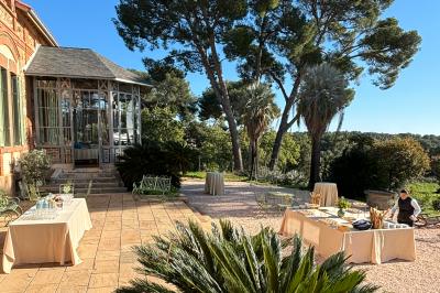 Miniature Location salle La Londe-les-Maures (Var) - Château de la Pascalette #10 Terrasse ensoleillée avec tables dressées pour un buffet, entourée de végétation et d'arbres imposants.