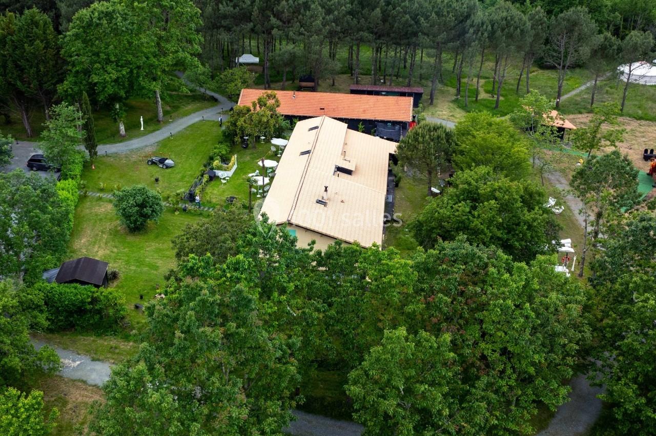 Vue aérienne d'un bâtiment avec toit orange entouré de verdure et d'arbres dans un cadre naturel.
