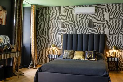 Salle de bain avec un grand miroir doré, deux vasques noires, robinetterie dorée et décoration moderne.