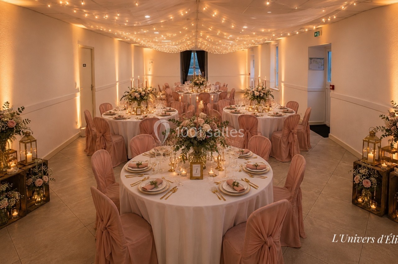 Salle de réception décorée avec des tables rondes, nappes blanches, chaises roses et éclairage chaleureux.