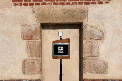 Borne photo avec anneau lumineux placée devant une entrée vitrée, entourée de tonneaux en bois.