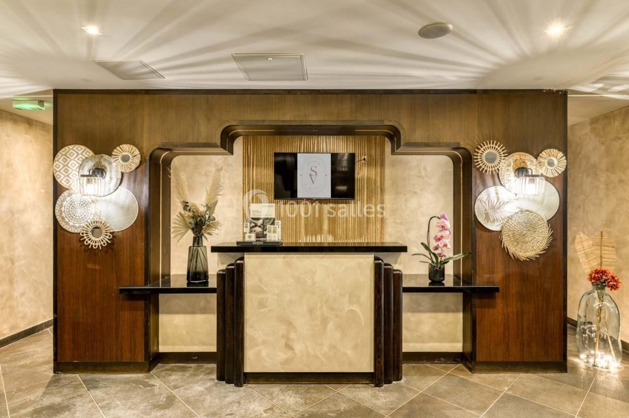 Comptoir d'accueil élégant avec décorations murales en bois, fleurs et éclairage tamisé dans un espace intérieur.