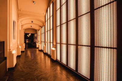 Couloir avec parquet en bois sombre, éclairé par des panneaux lumineux aux motifs géométriques.