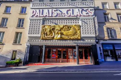 Miniature Façade du Palais des Glaces Salle avec moquette rouge, table en bois clair, chaises rouges et miroir éclairé par des ampoules.