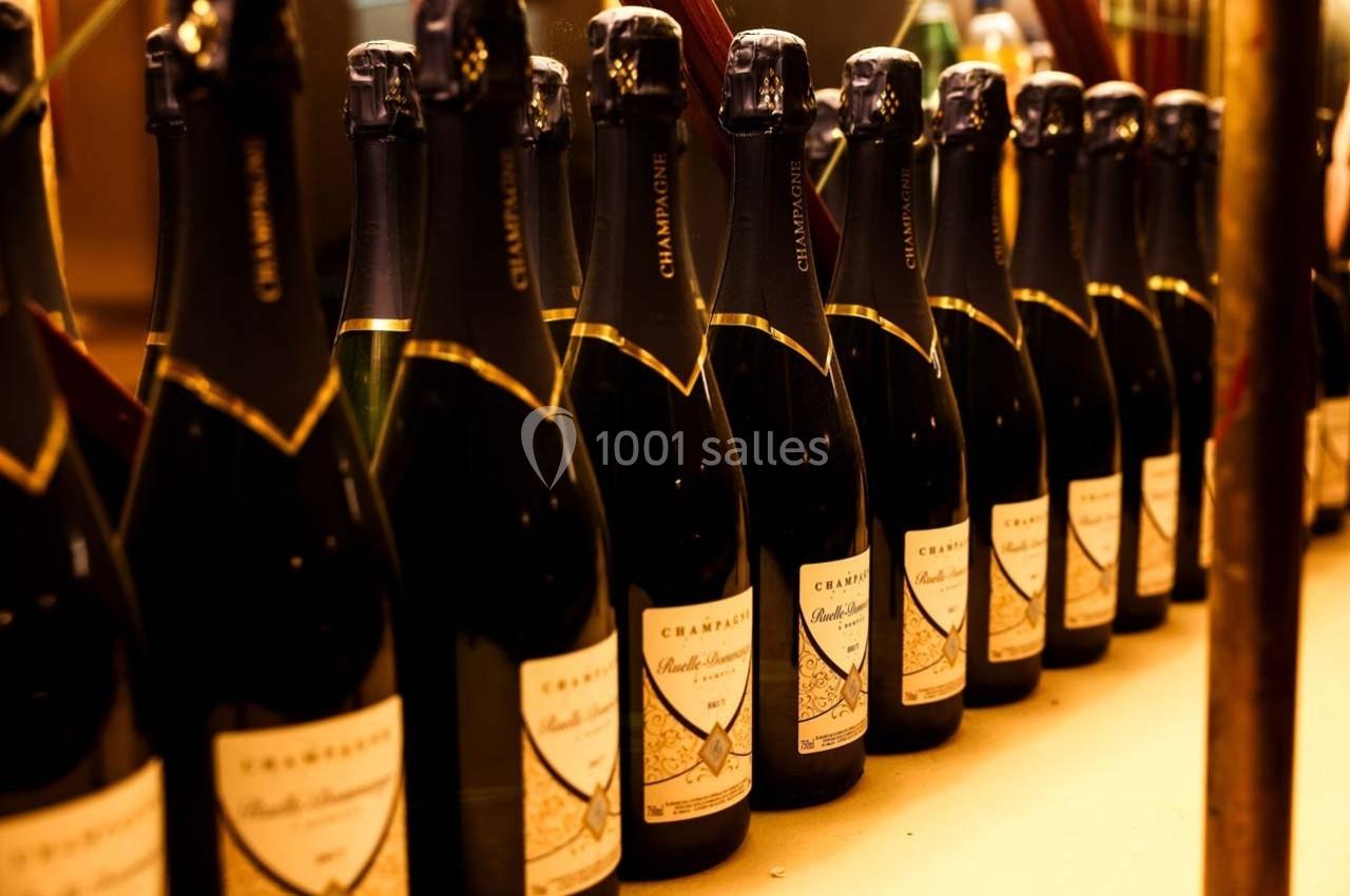 Le Grand bar du Palais des Glaces Bouteilles de champagne alignées sur une étagère, éclairées par une lumière chaude.