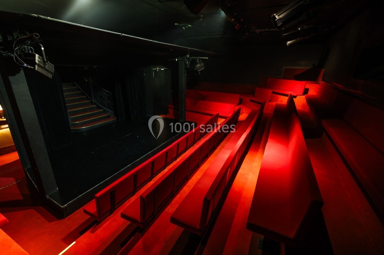 Petit Palais des Glaces Salle de théâtre sombre avec des sièges rouges en gradins et une petite scène noire éclairée.