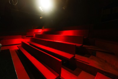 Miniature Petit Palais des Glaces Salle avec moquette rouge, table en bois clair, chaises rouges et miroir éclairé par des ampoules.