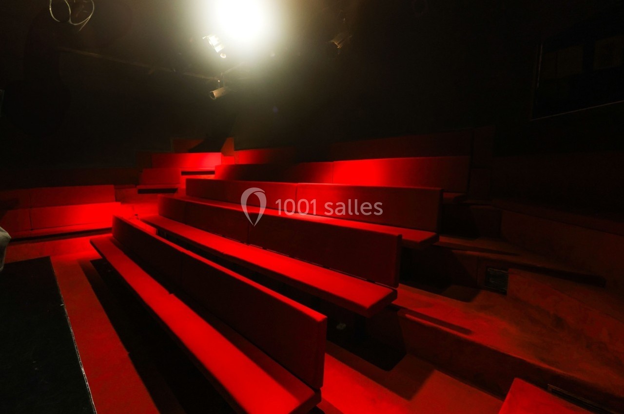 Petit Palais des Glaces Gradins vides en velours rouge éclairés par une lumière vive dans une salle sombre.