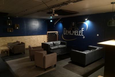 Deux micros sur pied dans une salle sombre, éclairée par un écran lumineux affichant un texte flou.