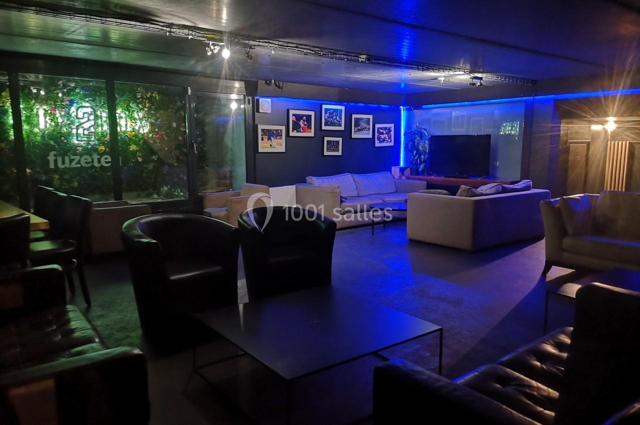 Salle de détente moderne avec canapés, fauteuils, tables basses, éclairage tamisé et décorations murales.