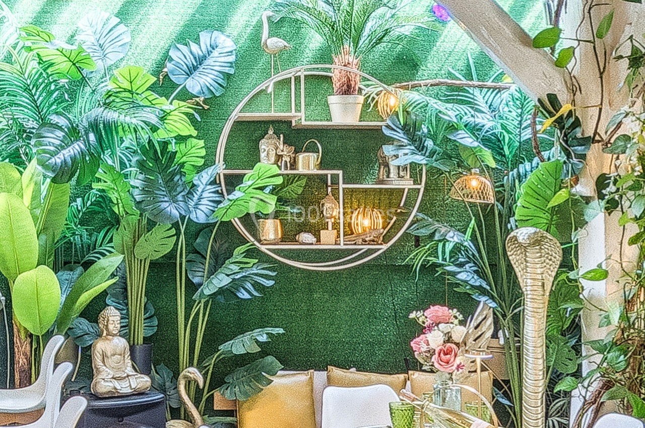 Mur végétal décoratif avec plantes tropicales, étagères circulaires, objets décoratifs et statue de Bouddha.