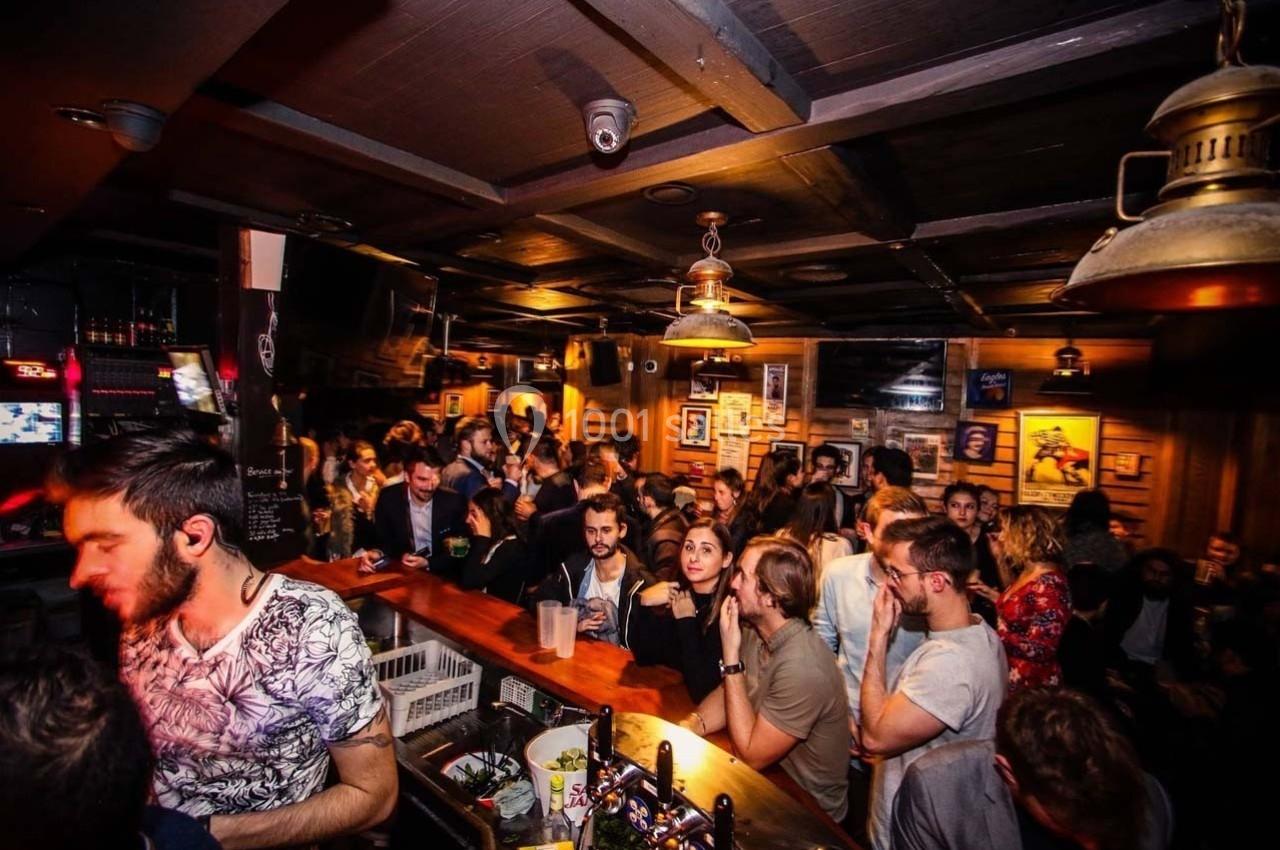 Un bar animé avec des clients discutant et profitant de l'ambiance sous un éclairage chaleureux.
