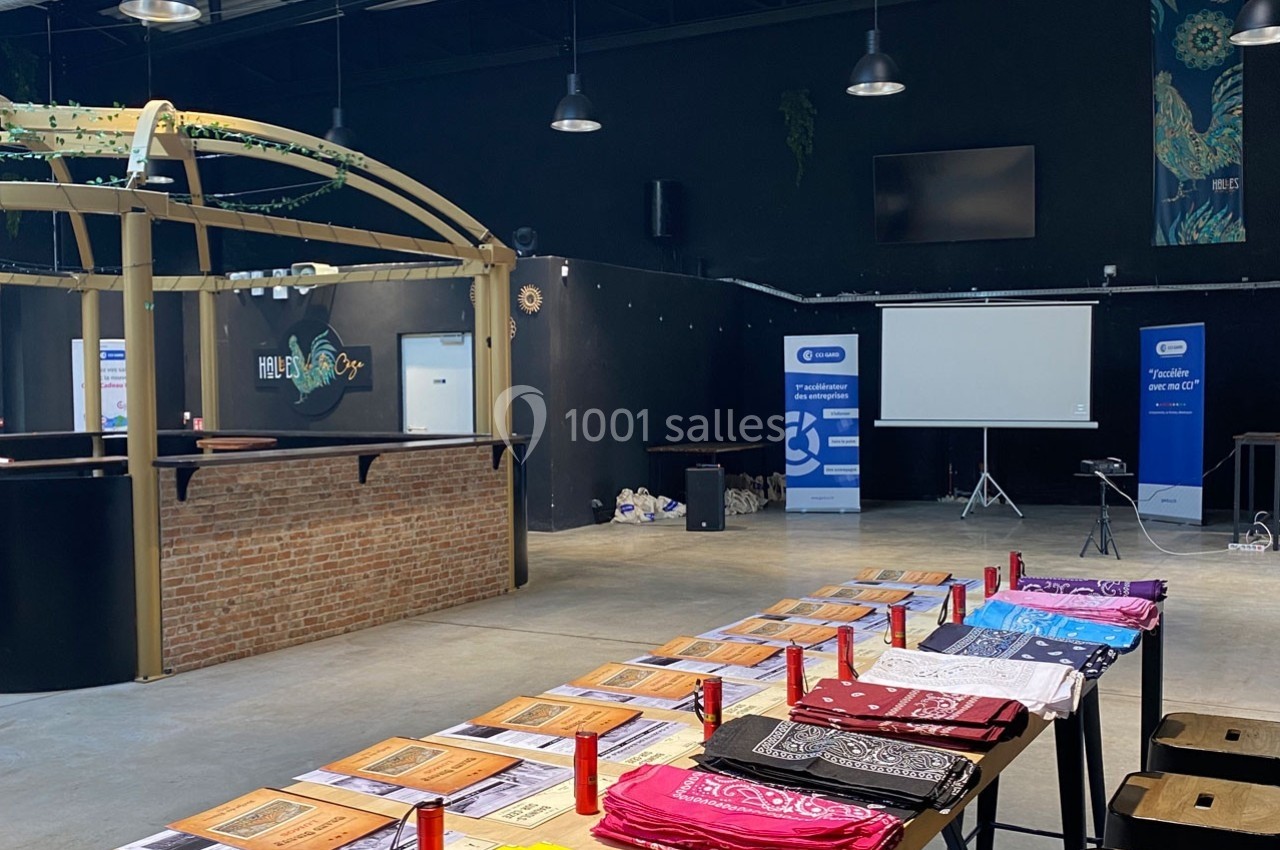 Salle aménagée avec des tables couvertes de brochures et de bandanas colorés, un écran de projection et des affiches en…