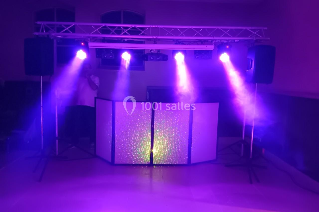 Installation de matériel de sonorisation et d'éclairage avec projecteurs violets dans une salle sombre.