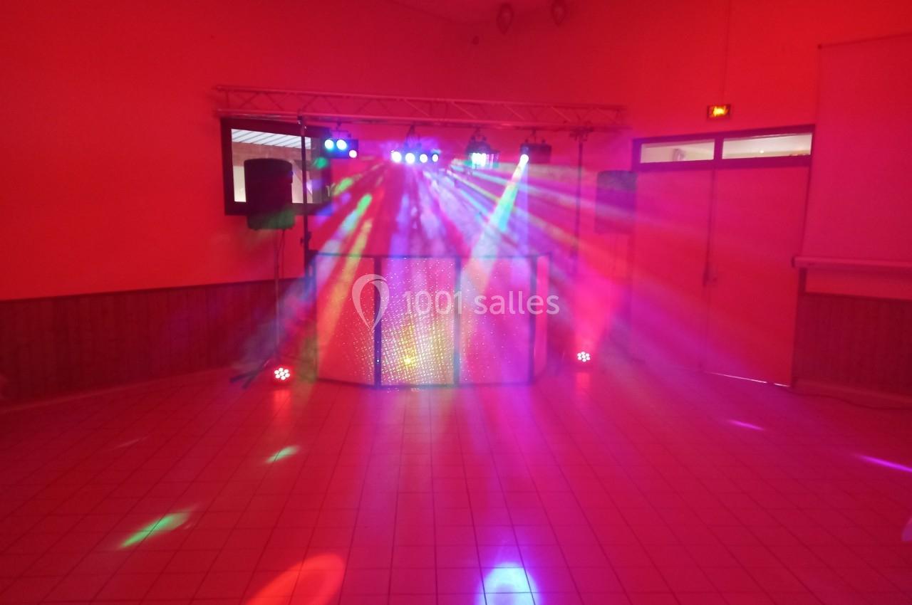 Jeux de lumières colorées projetés dans une salle avec un équipement de sonorisation et une piste de danse.