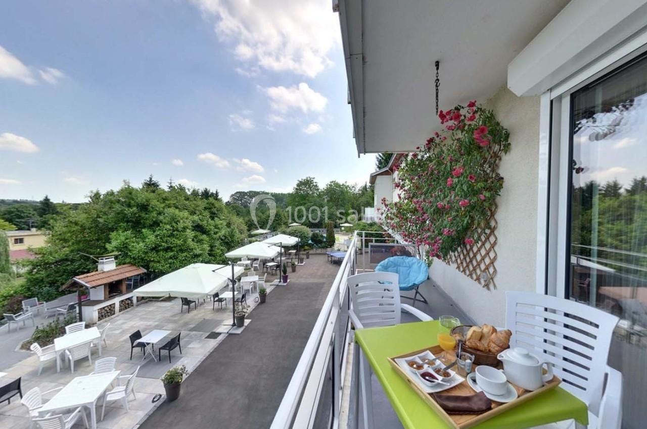 Petit-déjeuner servi sur un balcon avec vue sur une terrasse aménagée, des parasols et un paysage verdoyant.