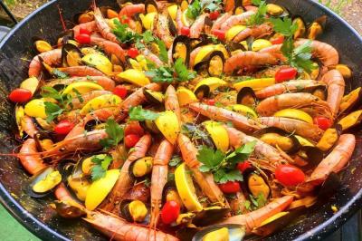 Salle lumineuse avec une grande table décorée de fleurs roses, entourée de chaises blanches, et un espace en arrière-plan.