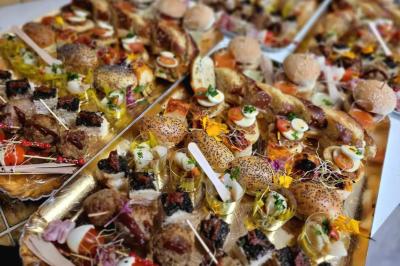 Salle lumineuse avec une grande table décorée de fleurs roses, entourée de chaises blanches, et un espace en arrière-plan.