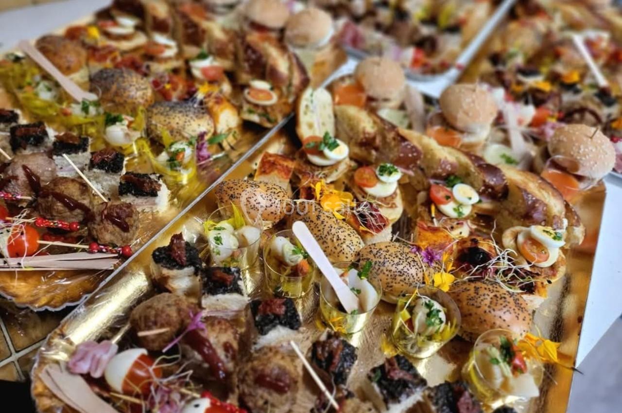 Plateaux garnis de divers amuse-bouches, incluant mini-burgers, brochettes, verrines et bouchées salées variées.