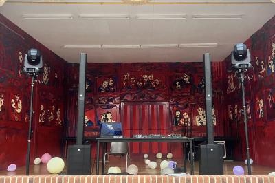 Pièce montée en choux décorée de fleurs en sucre et de motifs en chocolat blanc, posée devant un mur de briques.