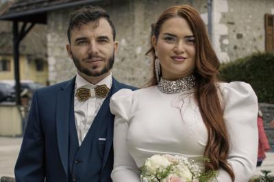 Pièce montée en choux décorée de fleurs en sucre et de motifs en chocolat blanc, posée devant un mur de briques.
