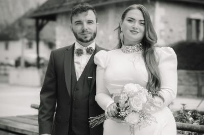 Pièce montée en choux décorée de fleurs en sucre et de motifs en chocolat blanc, posée devant un mur de briques.
