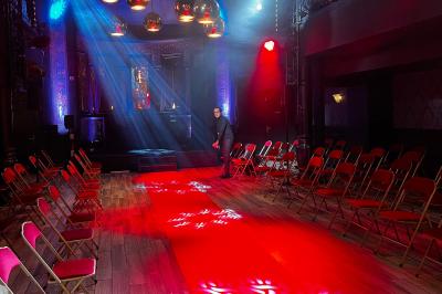 Deux faisceaux lumineux blancs traversent une salle sombre avec des murs en pierre apparente.