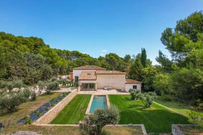Salon avec canapé beige, fauteuils, table basse, télévision, cheminée en pierre et plafond avec poutres apparentes.