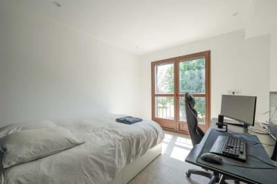 Salon avec canapé beige, fauteuils, table basse, télévision, cheminée en pierre et plafond avec poutres apparentes.