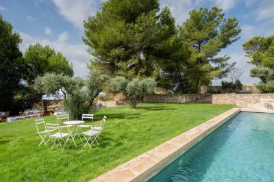Salon avec canapé beige, fauteuils, table basse, télévision, cheminée en pierre et plafond avec poutres apparentes.