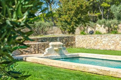 Salon avec canapé beige, fauteuils, table basse, télévision, cheminée en pierre et plafond avec poutres apparentes.