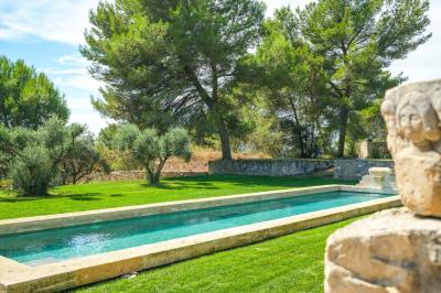 Salon avec canapé beige, fauteuils, table basse, télévision, cheminée en pierre et plafond avec poutres apparentes.