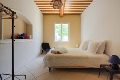 Salon avec canapé beige, fauteuils, table basse, télévision, cheminée en pierre et plafond avec poutres apparentes.