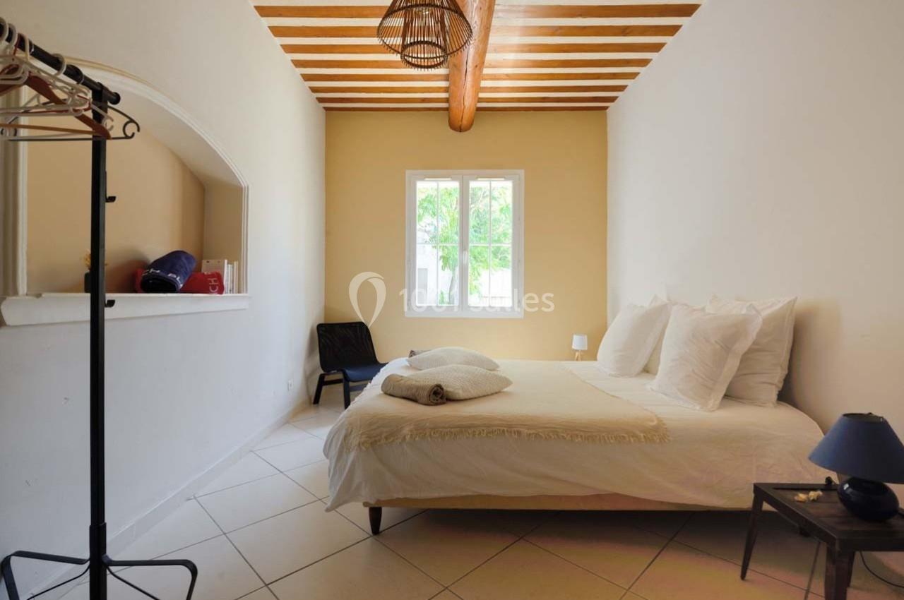 Chambre lumineuse avec lit double, plafond en bois, fenêtre donnant sur un jardin, et mobilier minimaliste.