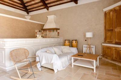 Salon avec canapé beige, fauteuils, table basse, télévision, cheminée en pierre et plafond avec poutres apparentes.