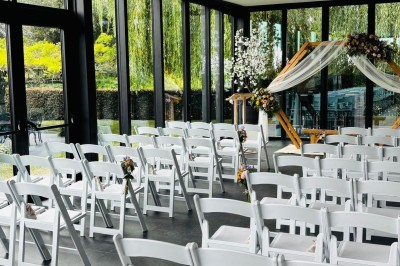 Étang entouré d'arbres et de buissons sous la neige, avec un lampadaire et des bancs dans un paysage hivernal.