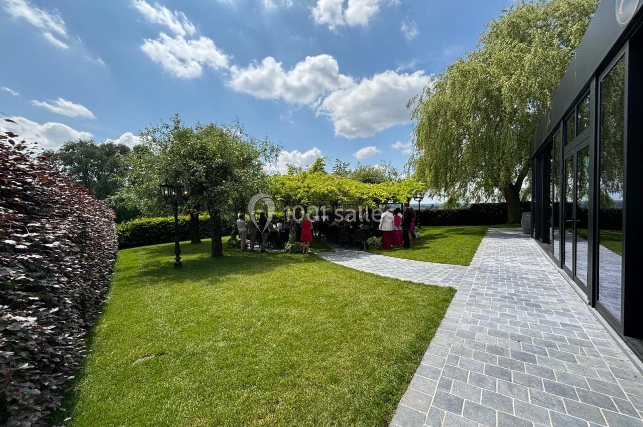 Groupe de personnes rassemblées sous une pergola dans un jardin verdoyant par une journée ensoleillée.