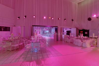 Miniature Grand Salon  Salle de réception décorée avec des fleurs blanches, des tables élégantes et un éclairage rose tamisé.